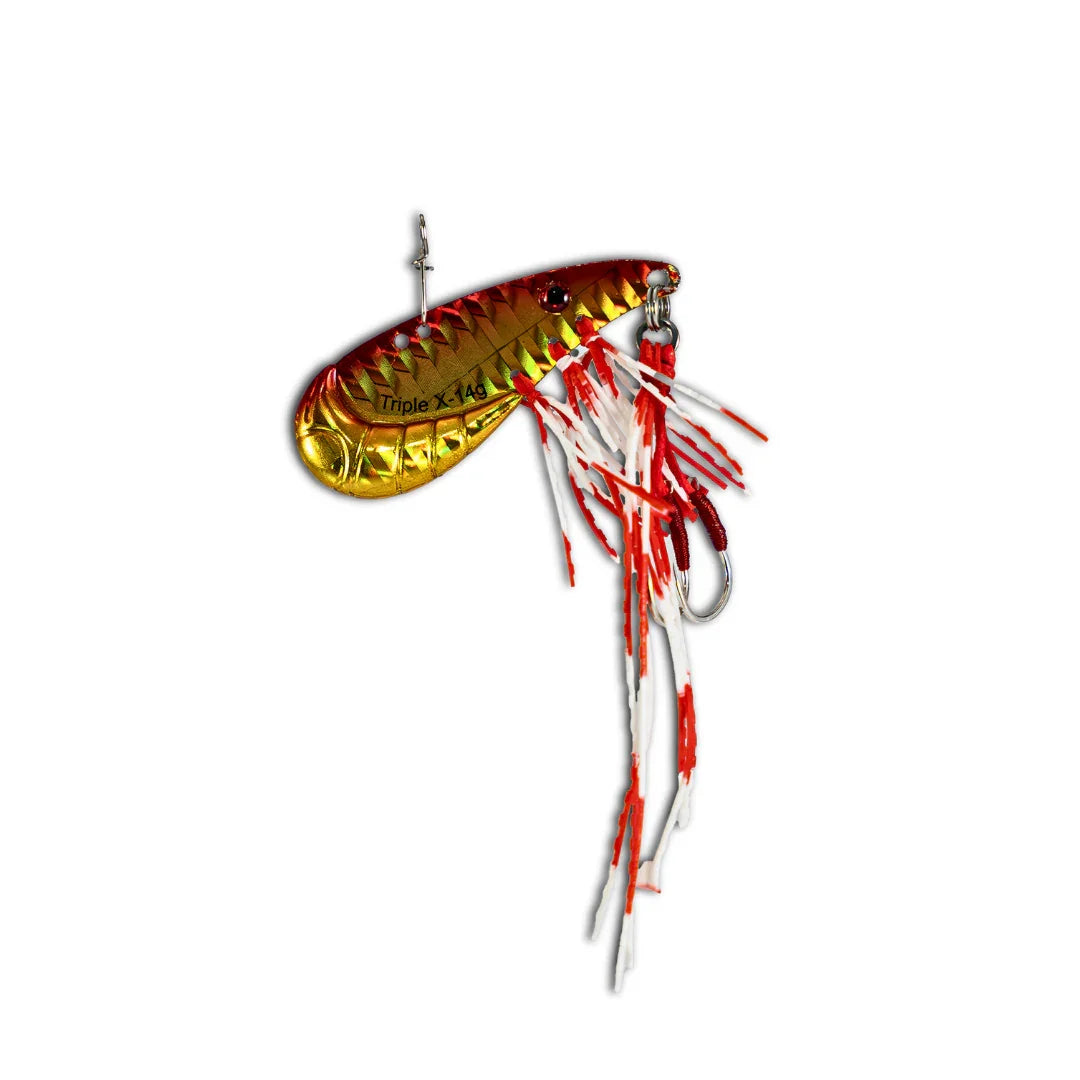 Gold and red handcrafted fishing lure with feathered skirt and sharp hook on white background